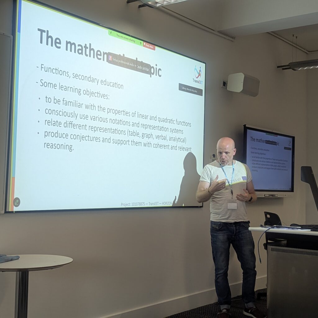 A speaker presenting a slide about mathematical learning objectives.