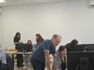 A workshop room with participants working on computers while workshop facilitators of the Educational Technology Lab help them.